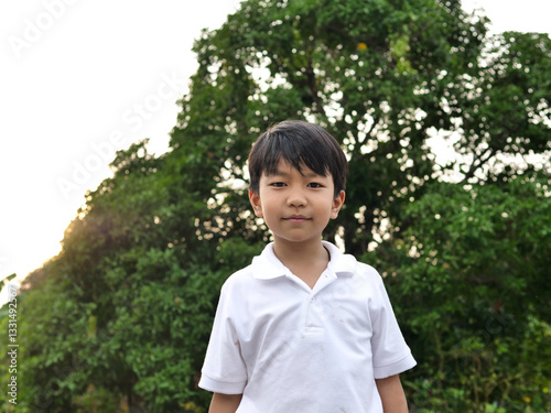 Asian handsome child boy smile with happy face outdoor in nature background. Happy kid in white shirt enjoy in relaxing day..Concept of health and happiness.