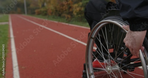 An athlete in a wheelchair is on the track, diligently preparing for an upcoming race