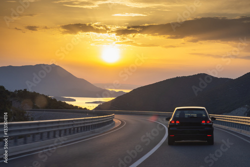 Road on Peljesac peninsula in Croatia, Europe. Scenic Road Trip: Driving into the sunset with mountains and water views on a winding coastal highway. Freedom and adventure awaits!
