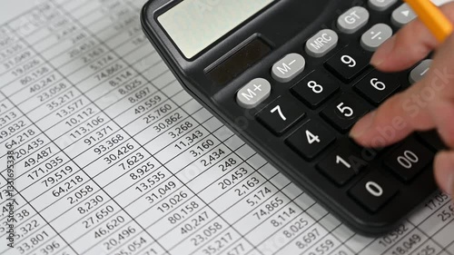 Hand Using Calculator on Financial Spreadsheet for Budgeting and Analysis