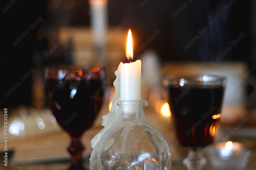 Books, lit candles, red wine, snacks and various deocration on the table. Dark academia or Halloween concept. Selective focus.