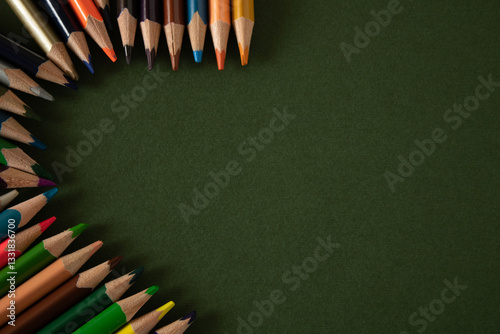 Stacked wooden colored pencils on a green school desk