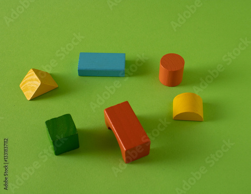 Wooden shapes of various colors left in the green grass.