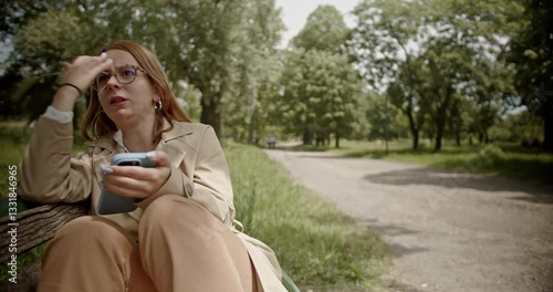 Young businesswoman experiencing work stress, arguing on a phone call in a park, showing frustration and disappointment