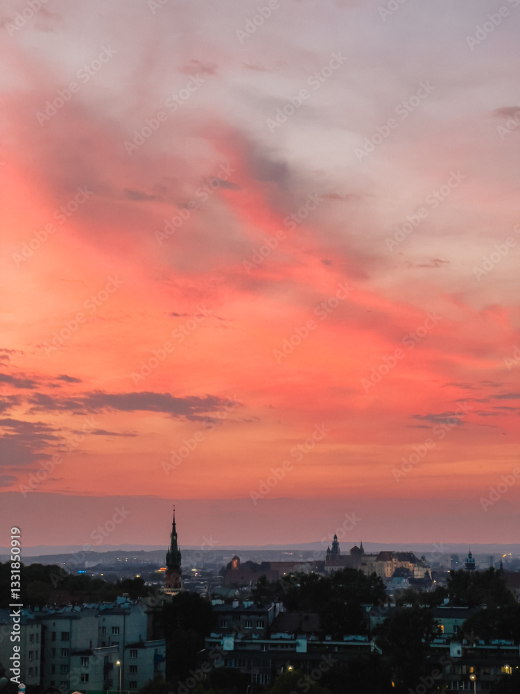 Fototapeta premium Wawel Royal Castle and Church of St. Catherine standing out against the Krakow skyline under a vibrant, burning sunset sky, creating a picturesque cityscape. burning sunset over Krakow, Poland