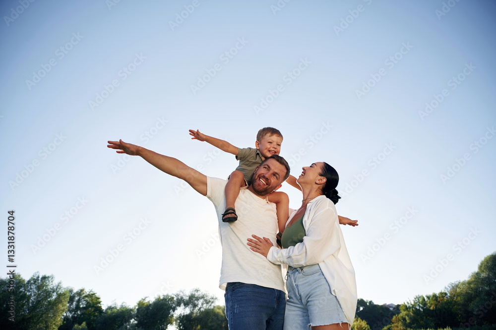 Hands to the sides, flying, imagination. Mother and father are with son outdoors on the field Hands to the sides, flying, imagination. Mother and father are with son outdoors on the field