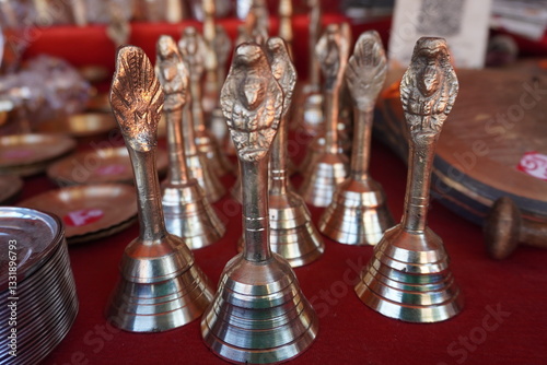 Several small, polished brass bells, likely Ghanti bells used in Hindu rituals which are commonly used during pooja ceremonies to create a sacred atmosphere and are believed to dispel negative energy