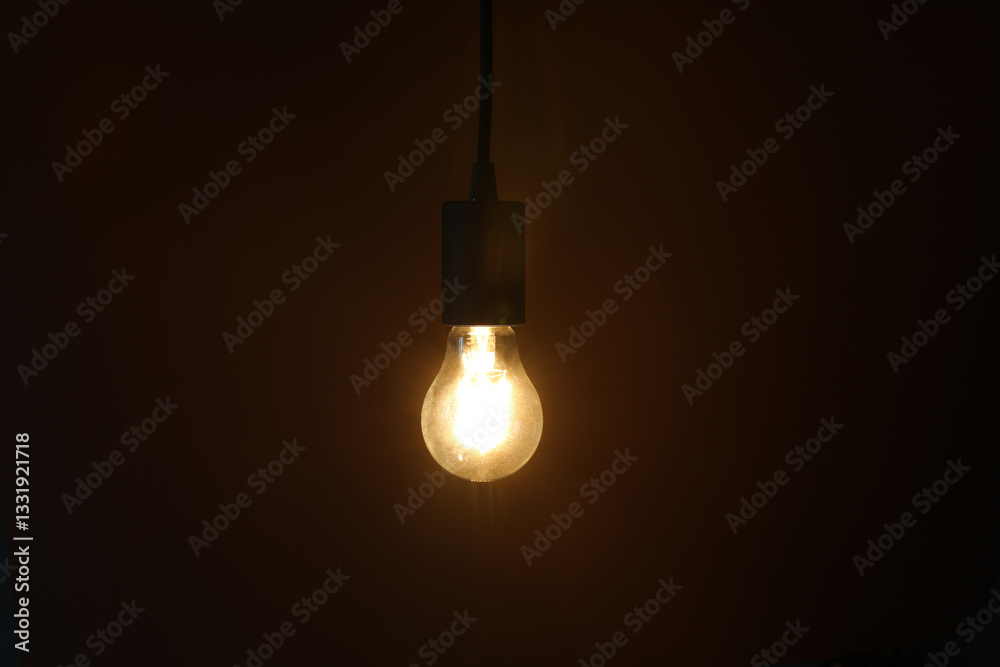 Glowing light bulb hanging on dark background Glowing light bulb hanging on dark background