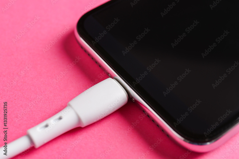 USB charge cable connected to smartphone on pink background, closeup USB charge cable connected to smartphone on pink background, closeup