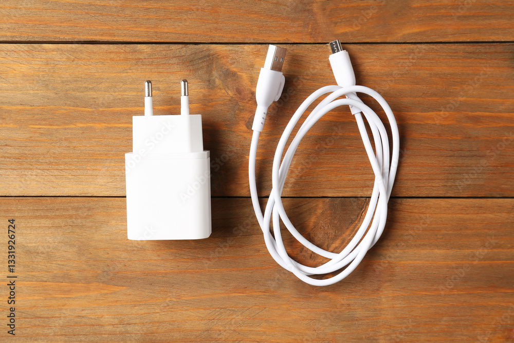 USB power adapter with charge cable on wooden table, top view USB power adapter with charge cable on wooden table, top view