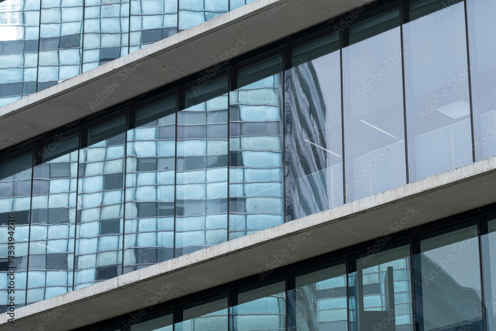 Close-up of a corporate building with continuous glass panels reflecting the surrounding skyscrapers and blue sky. Close-up of a corporate building with continuous glass panels reflecting the surrounding skyscrapers and blue sky.