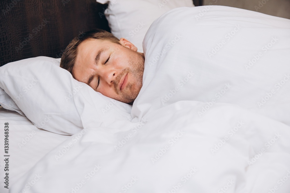 Man sleeping peacefully in bed covered by white sheets Man sleeping peacefully in bed covered by white sheets
