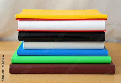 A stack of colorful notebooks on a wooden table. Perfect for education, office, or back to school concepts. photo