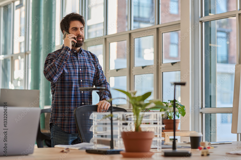 Fototapeta premium Businessman standing at his office desk and talking on a phone