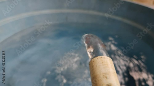 Clear water flows gracefully from the PVC pipe into the basin, creating ripples.
