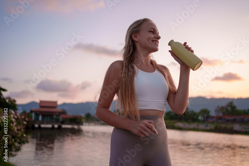 A fitness enthusiast enjoys refreshment and hydration while basking in the sunsets glow