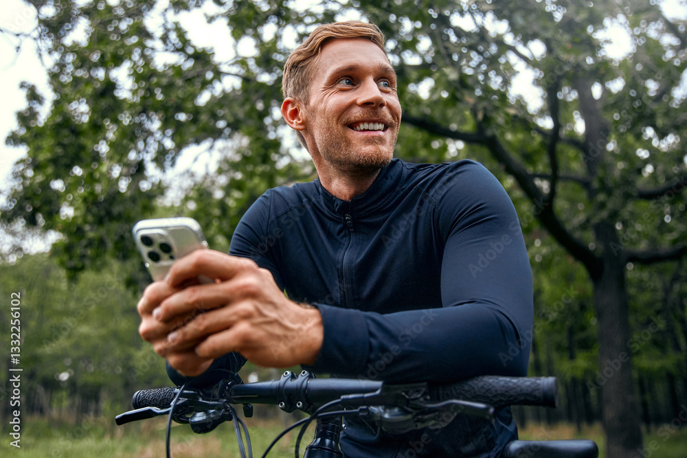 A Smiling Cyclist is checking their phone while enjoying the beautiful nature around them A Smiling Cyclist is checking their phone while enjoying the beautiful nature around them