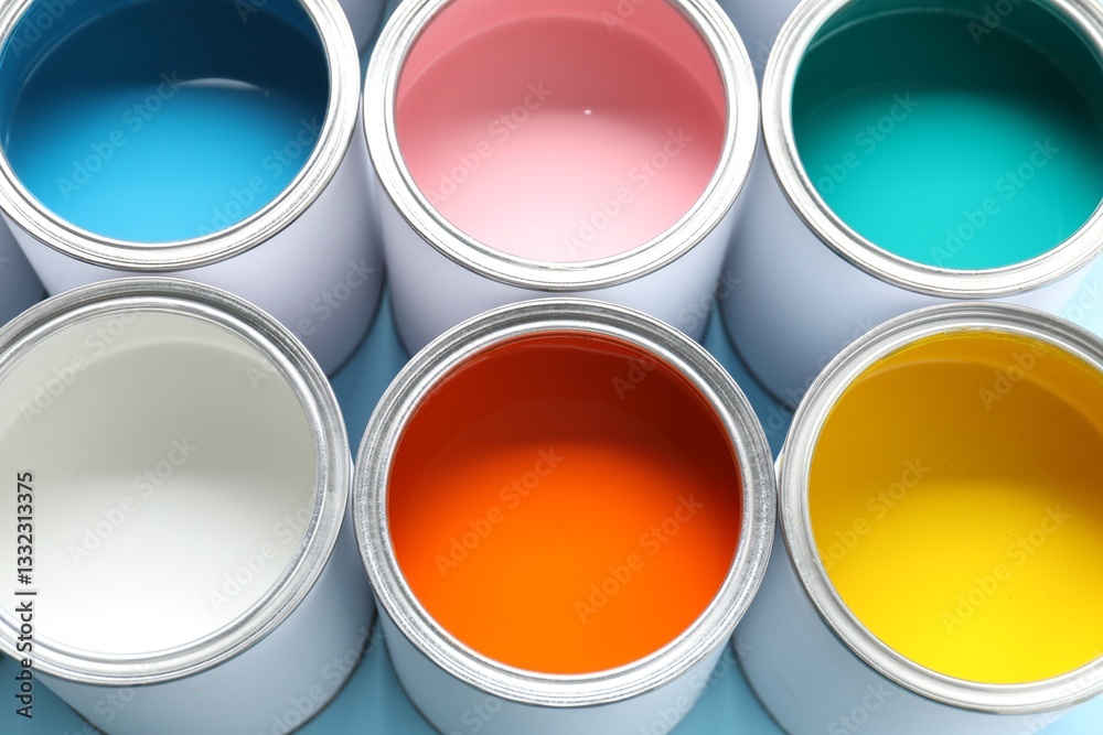 Cans of different paints on light blue background, closeup Cans of different paints on light blue background, closeup