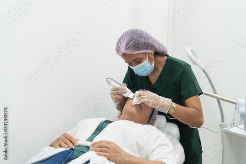 Beautician performing facial skin treatment on patient in clinic