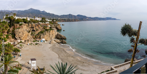 Panoramic view of Playa de Burriana, Nerja, with sandy beach, cliffs and distant mountains.