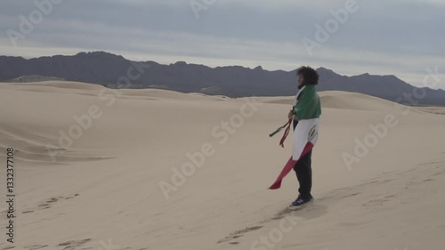 Brazilian man with afro hairstyle standing with the Mexican flag around his body in the desert photo