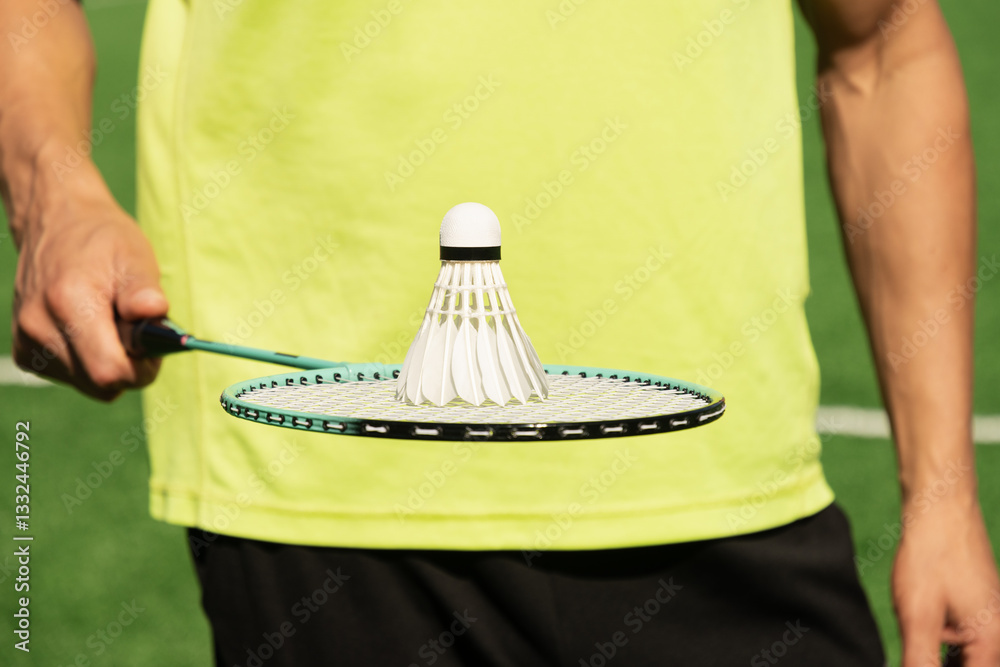 White badminton shuttlecock and badminton rackets in man hands. Summer sports game. Outdoor activity. Close up.