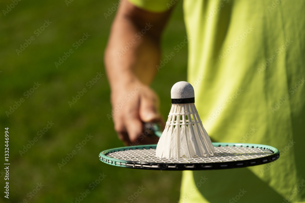 White badminton shuttlecock and badminton racket in man hands. Summer sports game. Outdoor activity. Close up. Copy space.