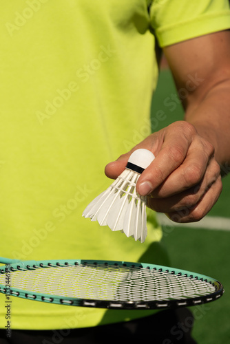 Obraz na płótnie White badminton shuttlecock and badminton rackets in man hands. Summer sports game. Focus on shuttlecock. Outdoor activity. Close up. Vertical. w salonie