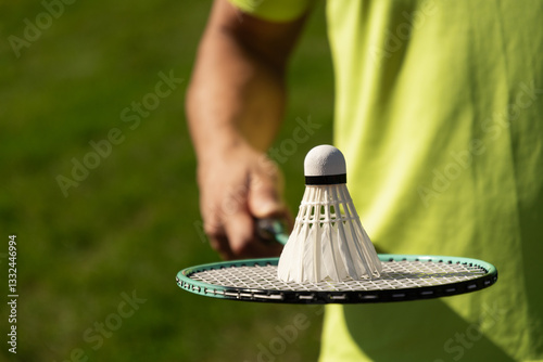 Obraz na płótnie White badminton shuttlecock and badminton racket in man hands. Summer sports game. Outdoor activity. Close up. Copy space. w salonie