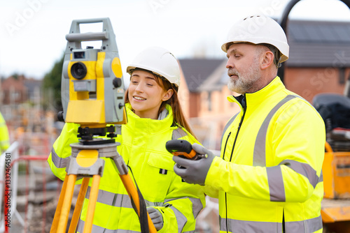 Construction team engages in surveying activity wearing safety gear at a building site 
