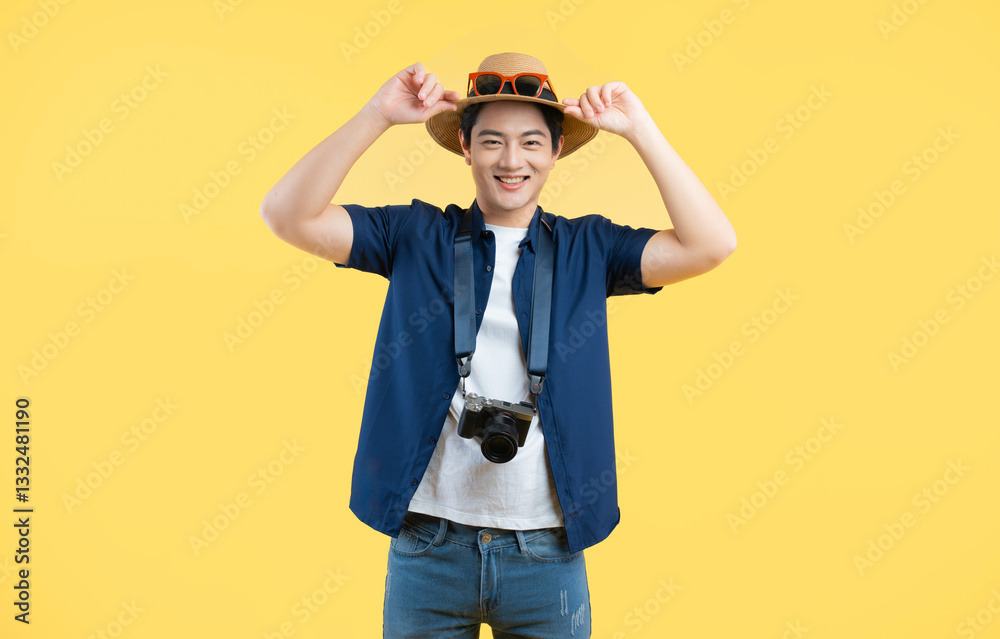 Portrait of young asian man using travel camera and posing on yellow background Portrait of young asian man using travel camera and posing on yellow background