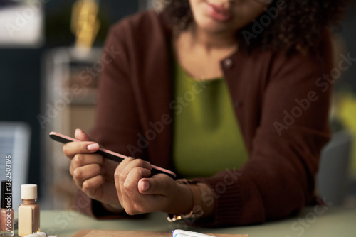Close-up of businesswoman using nail file to make manicure at her workplace in office