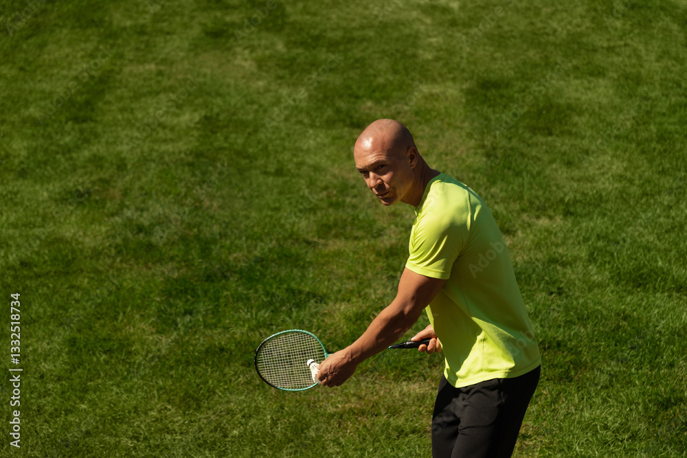 Strong caucasian badminton player racquet hit shuttlecock while practice before competition. Summer sports game, outdoors. Game moment.