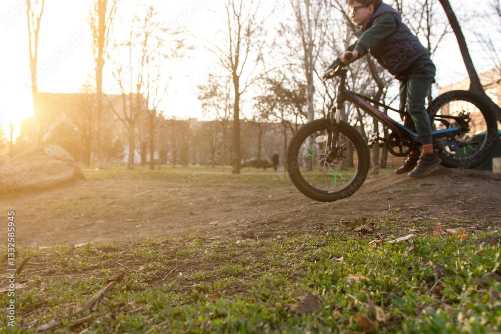 custom made wallpaper toronto digitalChild riding a bike in a park at sunset, jumping off a ramp with bare trees and golden sunlight in the background. Perfect for outdoor adventure and family fun photography.