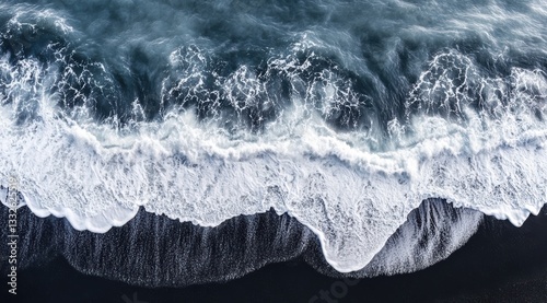 Drone shot of the ocean waves hitting against a black sand beach, drone photography