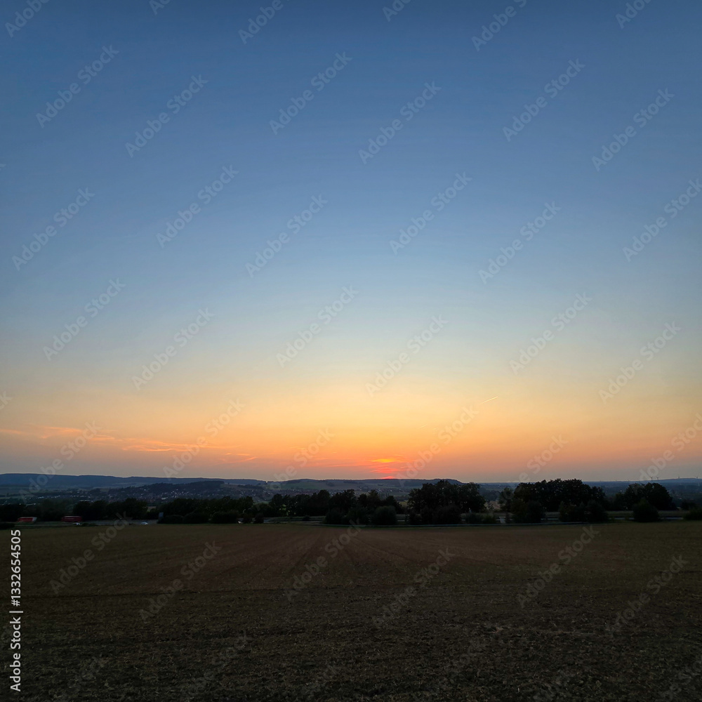 Fototapeta premium The serene sunset over tranquil fields is beautifully captured in its stunning splendor Deister Bad Nenndorf