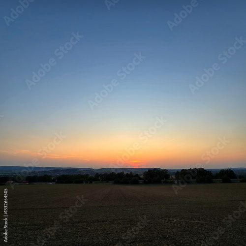The serene sunset over tranquil fields is beautifully captured in its stunning splendor Deister Bad Nenndorf