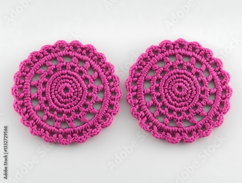 Two circular pink handmade crochet lace coasters appear on white