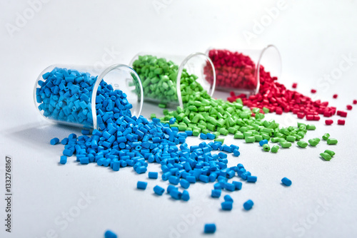 Blue, green and red masterbatch granules spilled from measuring cup, isolated on white background. Color pigment carrier polymer in plastic industry, suitable for plastic company catalog design