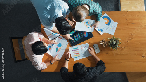 Top down aerial view of smart business people analyze data together at meeting. Group of business team working together and looking at financial chart at tablet placed on meeting table. Convocation.
