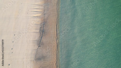 aerial drone view footage descending down onto a beach with turquoise water at sunset, summer concept background