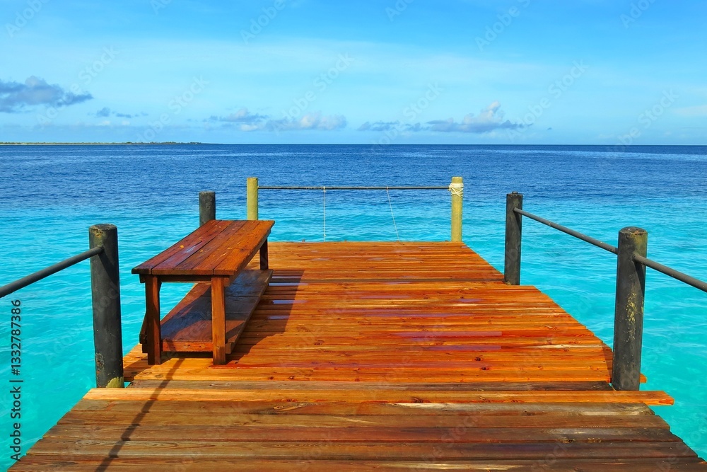 Fototapeta premium Wooden pier and bench with blue ocean in the background. Paradise pier under the tropical sky with azure sea.