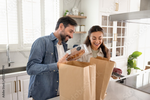 Photos Happy couple unpacking paper supermarket bags with bakery, organic products, pro