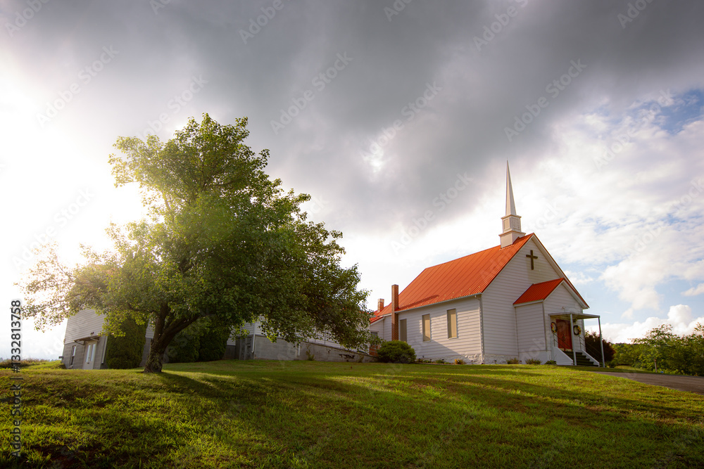 Fototapeta premium Church landscape with light breaking out from behind clouds