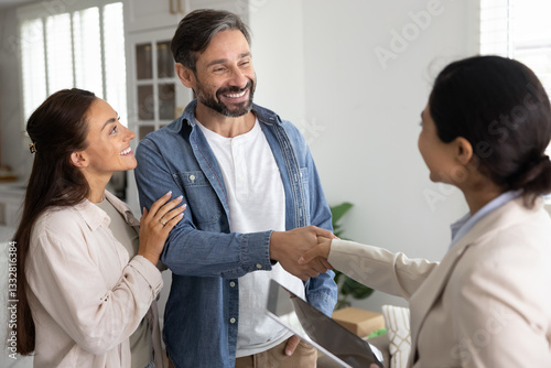 Quadro su tela Couple of positive satisfied property buyers giving handshake to female Indian r