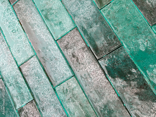 top view of a tile floor in green and gray tones wet by the rain with a diagonal structure.
