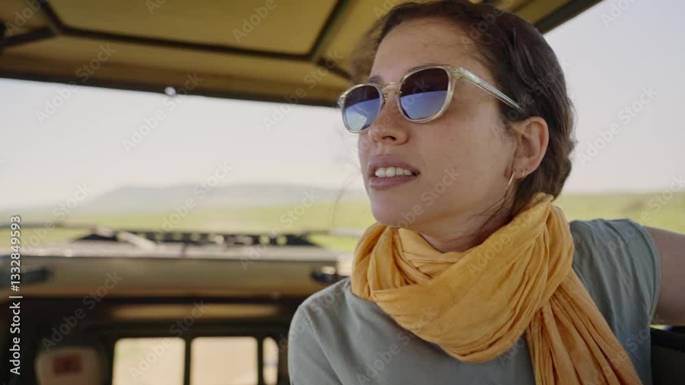 Driving in safari truck with open roof is young female tourist in vacation. Happy and smiling looking at wild animals and amazing view and landscape of Serengeti Park in Tanzania as car is driving Driving in safari truck with open roof is young female tourist in vacation. Happy and smiling looking at wild animals and amazing view and landscape of Serengeti Park in Tanzania as car is driving