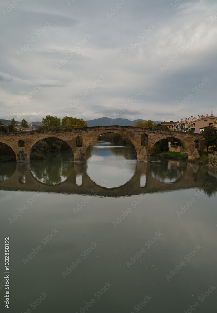 Fototapeta premium Puente de la Reina or Gares Bridge with its reflection in the Arga River, located in Navarra. The iconic Bridge of the Pilgrims of the Camino de Santiago Frances, route that comes from the Fances side
