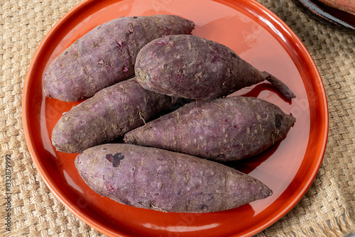 Colorful sweet-tasting tuberous roots vegetables purple and orange organic sweet potatos close up