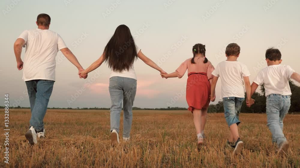 Caring parents and little children run joining hands along field at sunset time. Happy parents with children run enjoying family activity in park. Cute children with parents play on family vacation Caring parents and little children run joining hands along field at sunset time. Happy parents with children run enjoying family activity in park. Cute children with parents play on family vacation